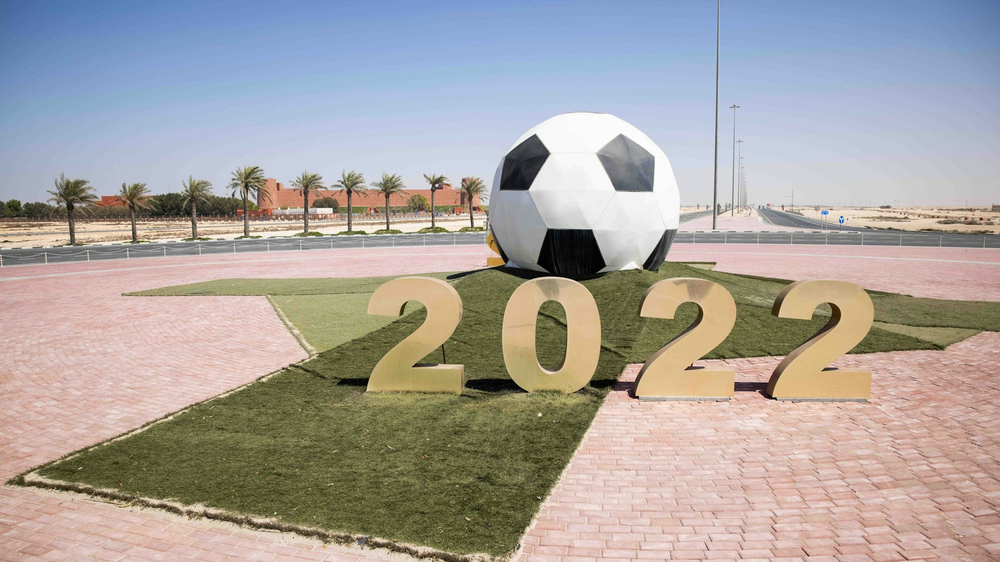Ein großer Ball mit der Jahreszahl 2022 steht auf einer Verkehrsinsel mit Kreisverkehr vor dem Trainigsgelände Al-Shamal sports Club in der Hafenstadt Al Ruwais.