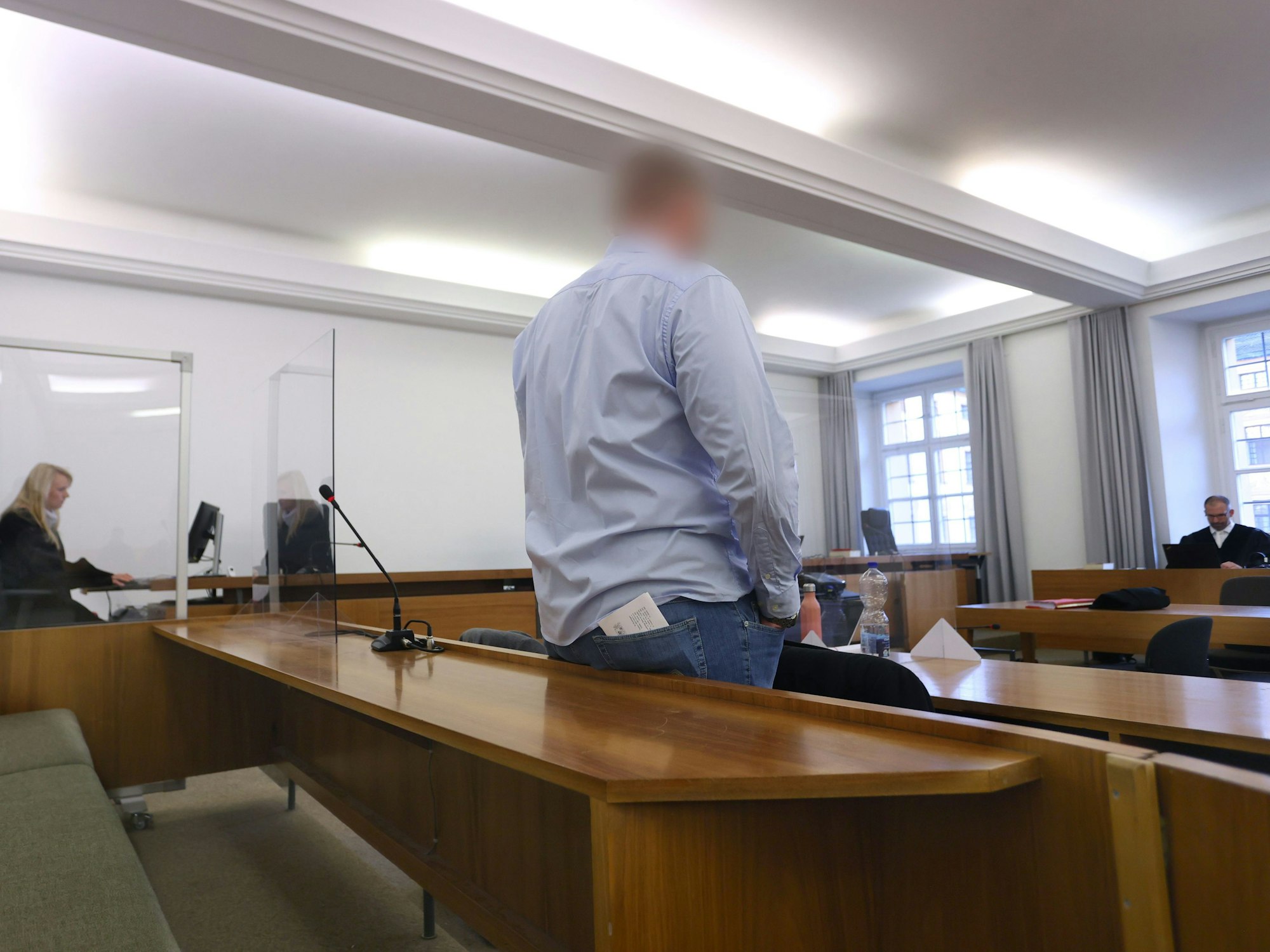 Mann steht in der Anklagebank in einem Verhandlungsraum. Er soll eine Kollegin bei einem Bundeswehr-Einsatz vergewaltigt haben.