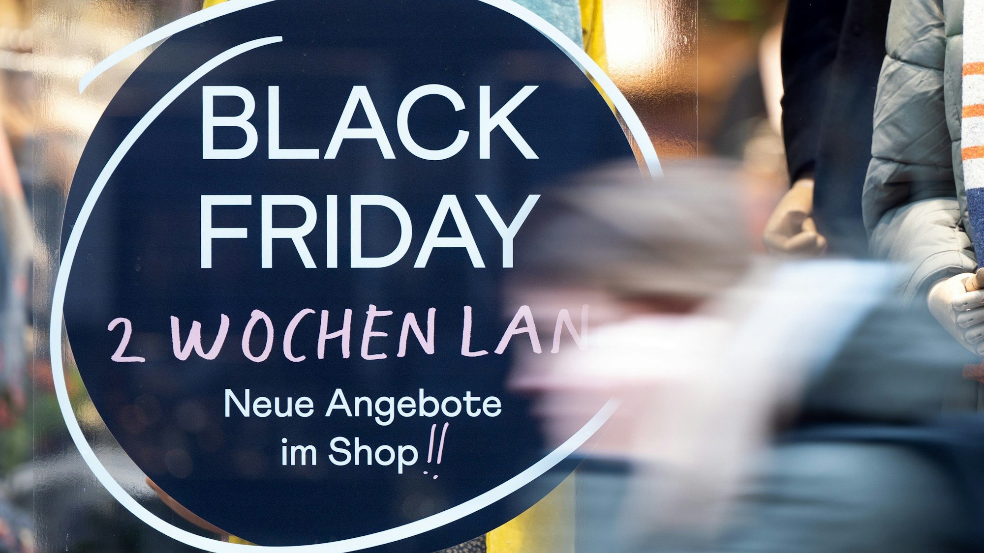 Eine Frau geht an einem Geschäft vorbei, das mit Black Friday-Angeboten wirbt.