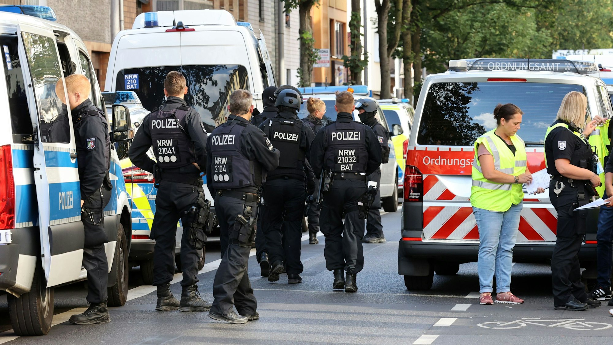 Polizei und Ordnungsamt stehen bei einer Razzia in Köln-Kalk auf der Straße.
