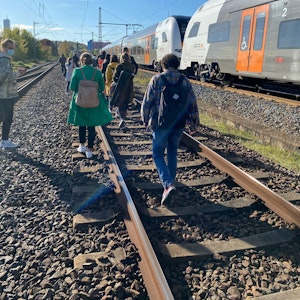 Fahrgäste des RE6 in Köln gehen zu Fuß über die Gleise in Richtung Köln-Nippes.