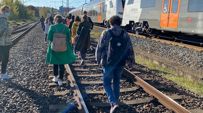 Fahrgäste des RE6 in Köln gehen zu Fuß über die Gleise in Richtung Köln-Nippes.