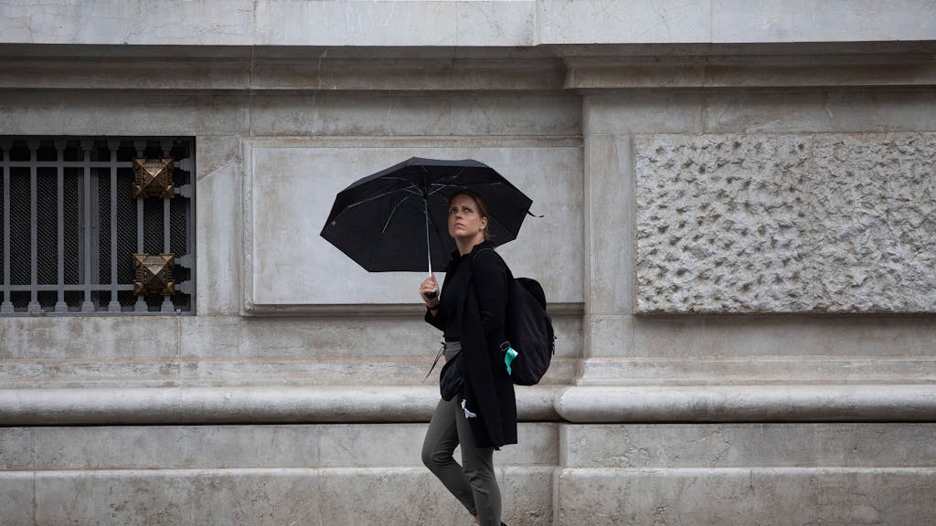 Eine Frau schützt sich in Sevilla unter ihrem Regenschirm vor dem Regen.