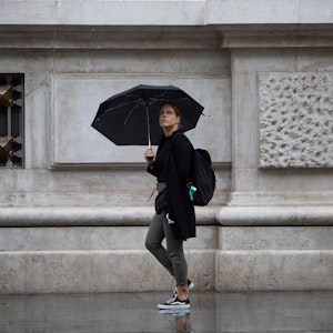 Eine Frau schützt sich in Sevilla unter ihrem Regenschirm vor dem Regen.