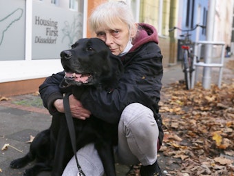 Gisa März kniet auf dem Bürgersteig mit ihrem Hund „Balu“.