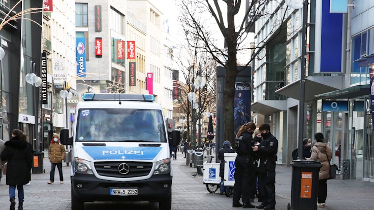 Einsatzkräfte und ein Auto der Polizei stehen auf der Schildergasse in Köln.