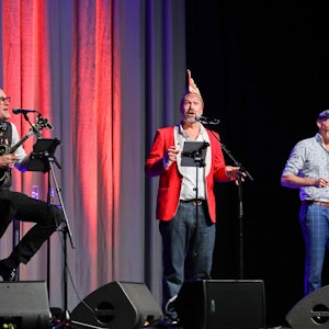 JP Weber, Volker Weininger und Martin Schopps gemeinsam auf der Bühne mit Gitarre und Mikrofonen.