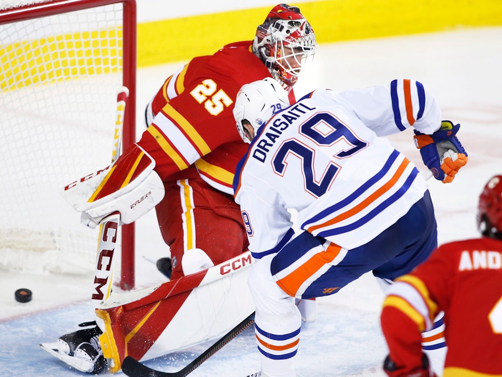 Edmonton Oilers Leon Draisaitl (r.) legt Puck an Calgary-Flames-Keeper Jacob Markstrom vorbei ins Tor.