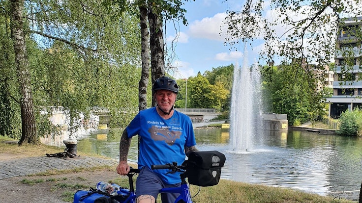 Oliver Trelenberg steht mit seinem Fahrrad vor einem See.