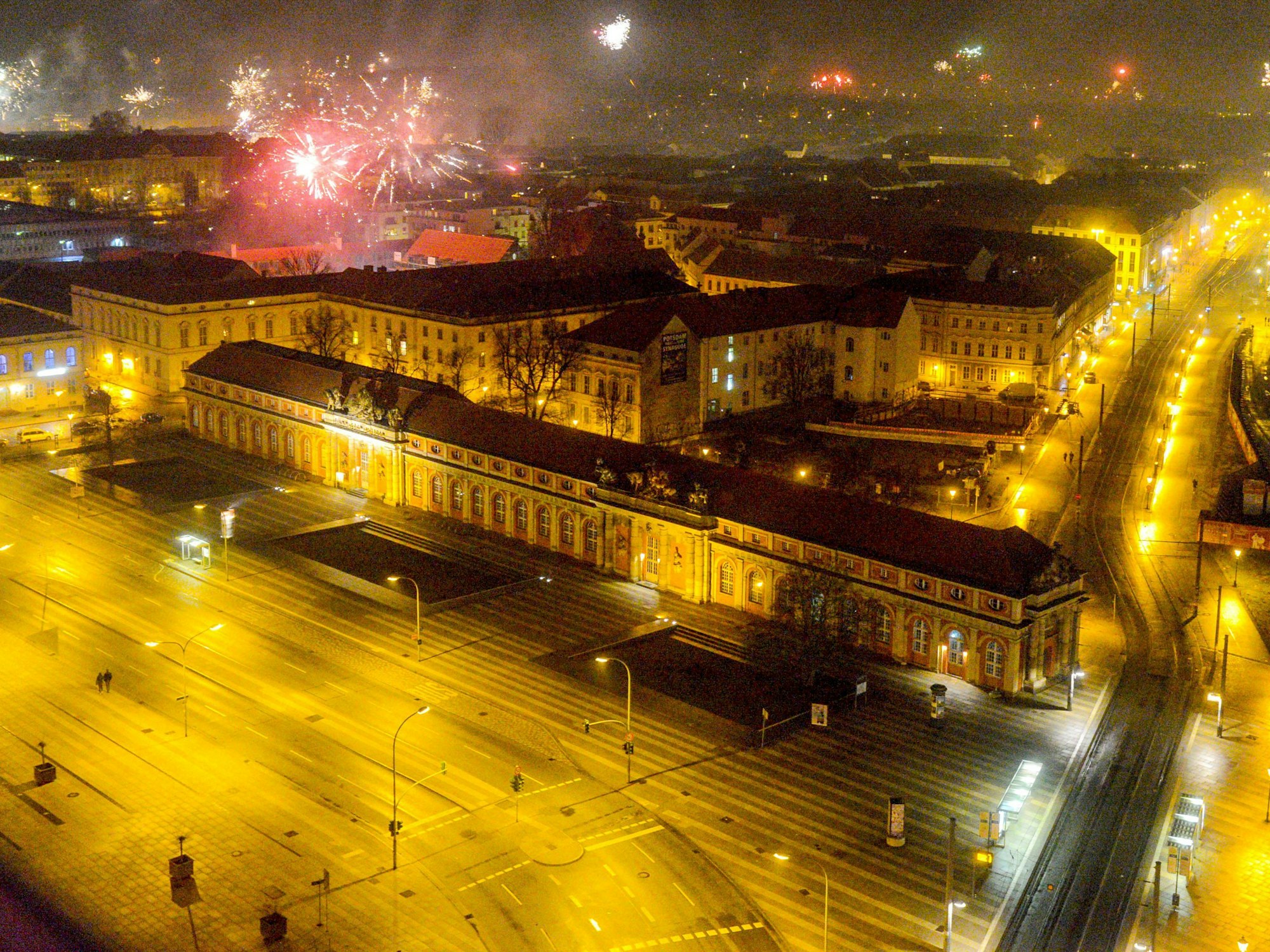 Blick vom Potsdamer Hotel Mercure auf die beleuchtete Breite Straße und das Filmmuseum, während in der Silvesternacht 2019 Feuerwerk in den Nachthimmel aufsteigt.