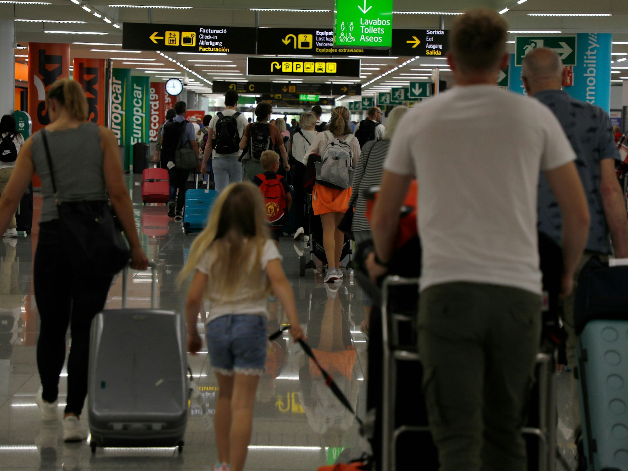 Menschen kommen mit Gepäck auf dem Flughafen von Palma de Mallorca an.