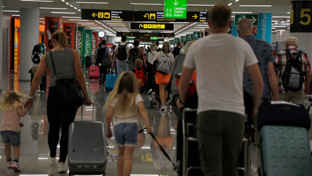 Menschen kommen mit Gepäck auf dem Flughafen von Palma de Mallorca an.