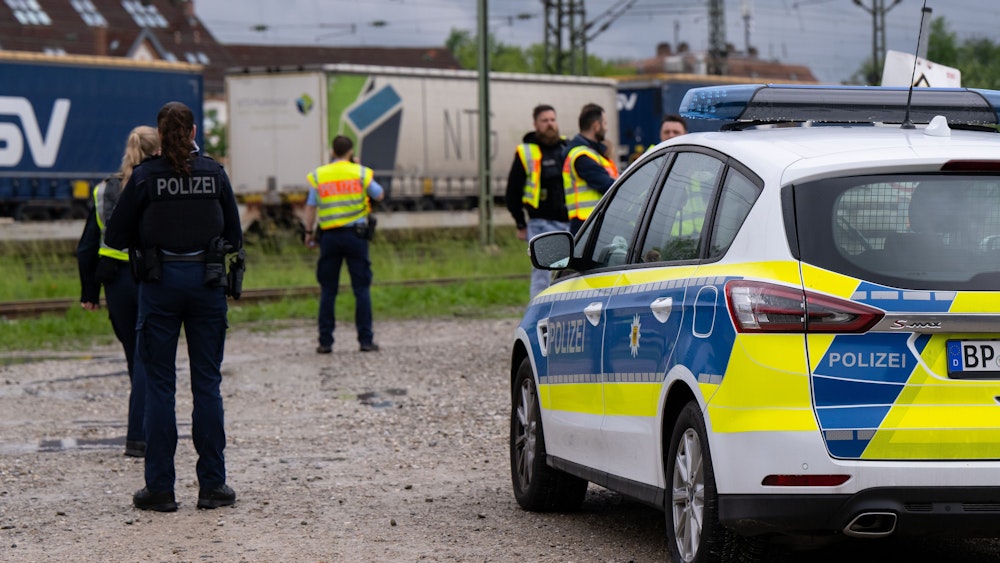 Einsatzkräfte der Polizei und Bundespolizei stehen an den Gleisen. Im Hintergrund ist ein Güterzug.