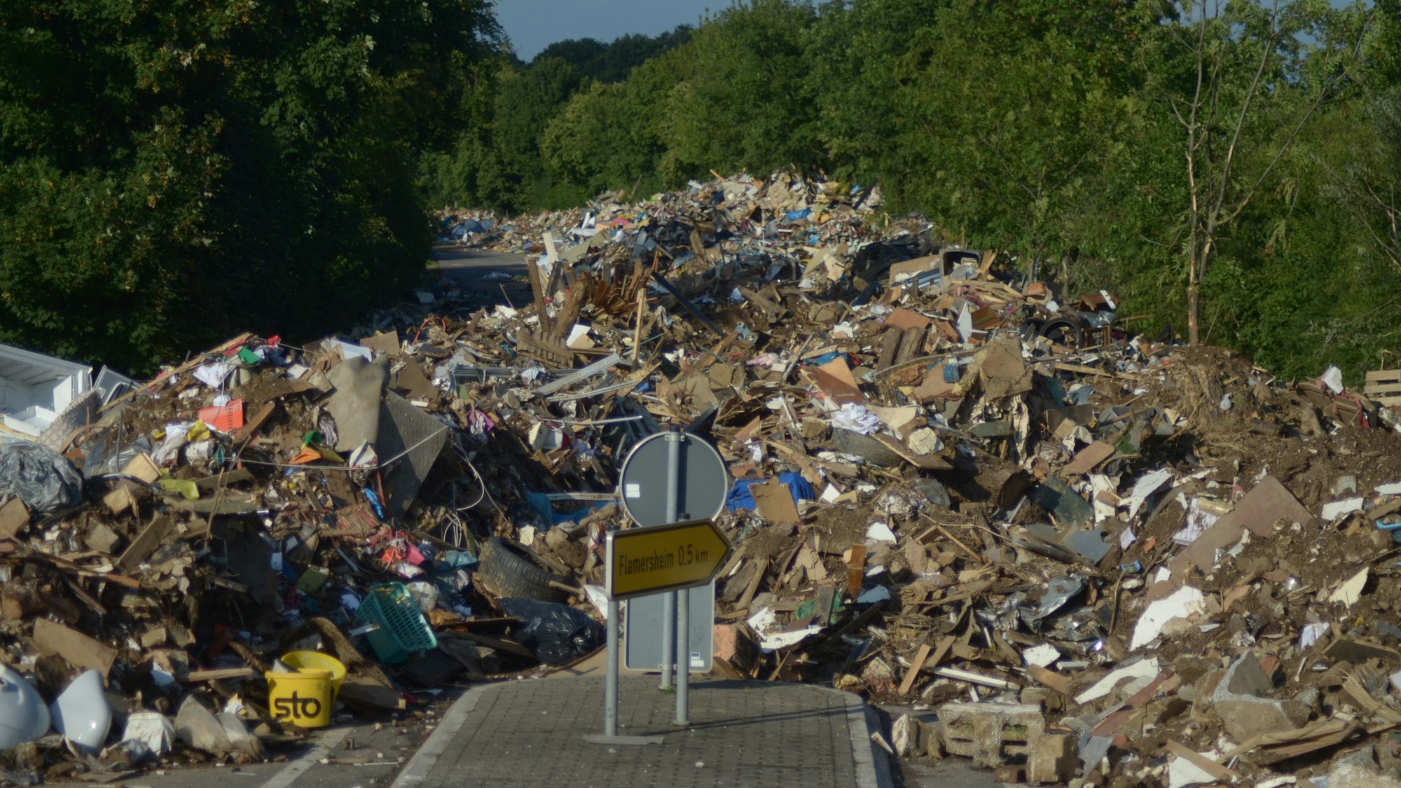 Auf der Straße von Flamersheim nach Kirchheim im Kreis Euskirchen türmt sich nach der Flutkatastrophe im Juli 2021 der Müll.
