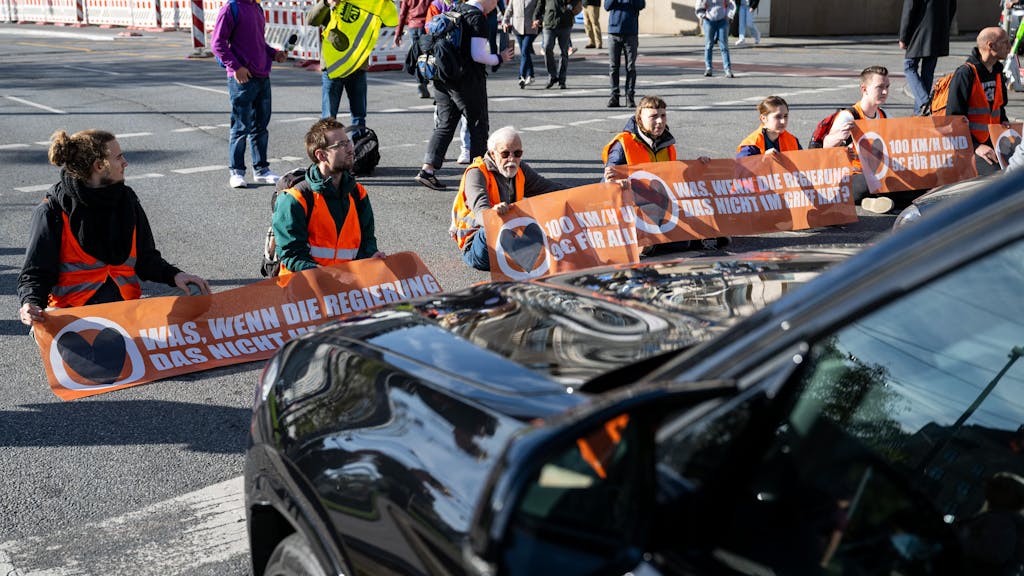 Klimaaktivisten haben sich am Karlsplatz in der Münchner Innenstadt auf die Fahrbahn geklebt und blockieren die Straße.