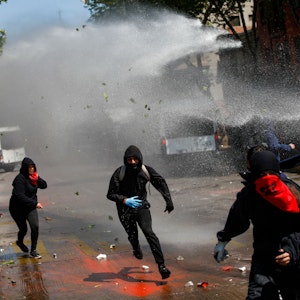 Demonstranten fliehen vor Wasserwerfern der Polizei.