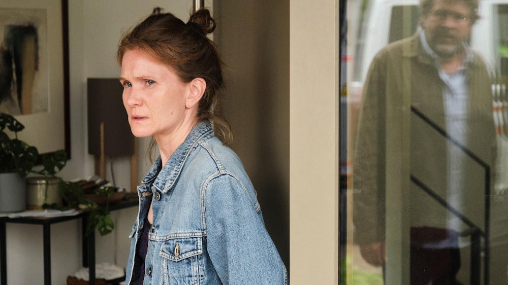 Sandra Vogt (Lisa Hagmeister) steht in der Terassentür eines Hauses. Ermittler Friedemann Berg (Hans-Jochen Wagner) ist in der Spieglung des Fensters zu sehen.