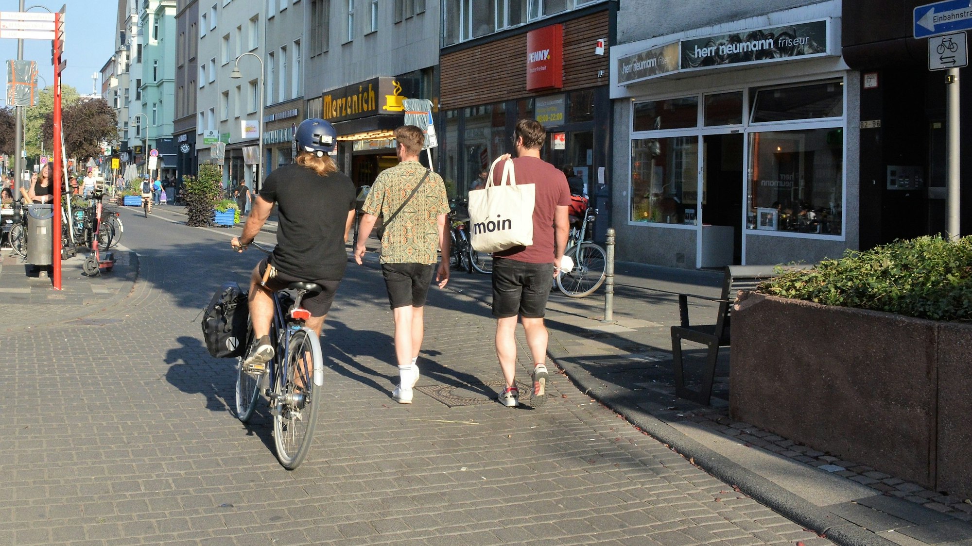 Ein Radfahrer und zwei Fußgänger laufen nebeneinander auf der Deutzer Freiheit.