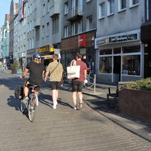 Ein Radfahrer und zwei Fußgänger laufen nebeneinander auf der Deutzer Freiheit.