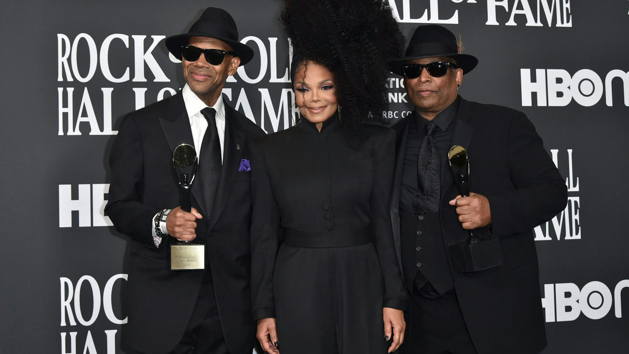 Jimmy Jam und Terry Lewis, in schwarzen Anzügen, halten ihre Auszeichnungen. In der Mitte steht Janet Jackson mit Hochsteckfrisur und schwarzem Hosenanzug.