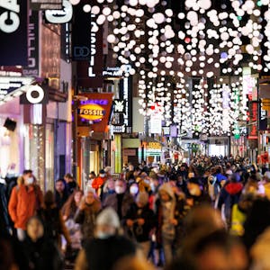 Passanten streifen durch die von Weihnachtsbeleuchtung gesäumte Hohe Straße in Köln.&nbsp;