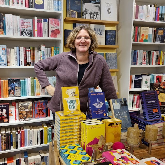 Ute Hentschel steht hinter Büchertischen in ihrer Buchhandlung in Burscheid