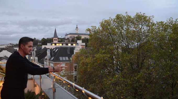 Jaroslaw Plichta blickt von seiner Wohnung im Dachgeschoss auf Bäume. Im Hintergrund sind Gebäude in Siegburg zu sehen.