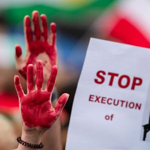 Menschen nehmen am „Marsch für die Freiheit“ teil und haben sich die Hände rot angemalt. Auf einem Plakat wird das Ende von Hinrichtungen gefordert.
