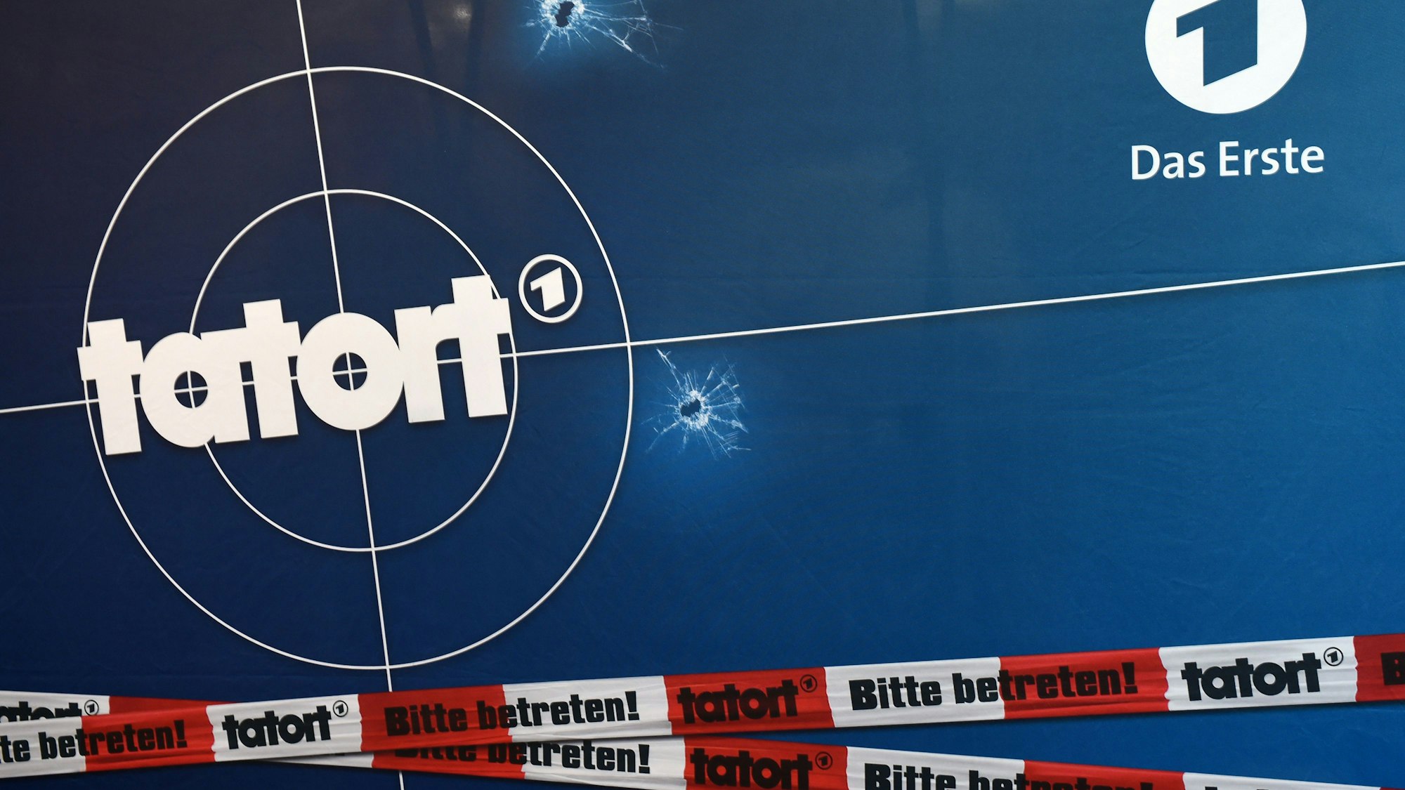 Auf einer Fotorückwand sind das Logo der ARD-Fernsehreihe „Tatort“.