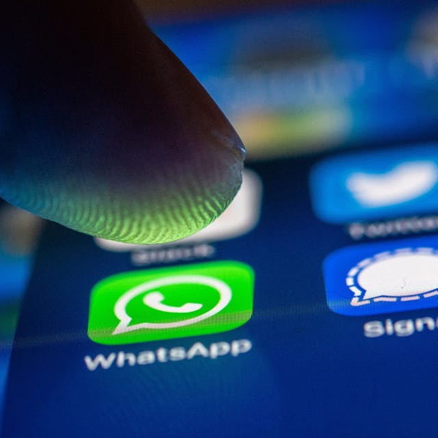 Ein Finger tippt auf dem Bildschirm eines Smartphones auf das Whatsapp-Icon.