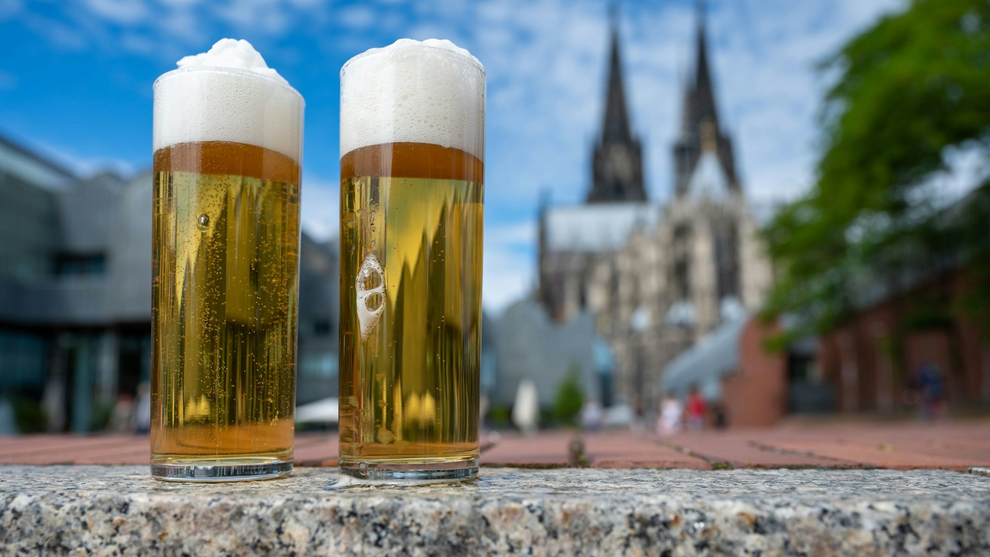 Kölsch im Glas, im Hintergrund ist der Kölner Dom zu sehen.