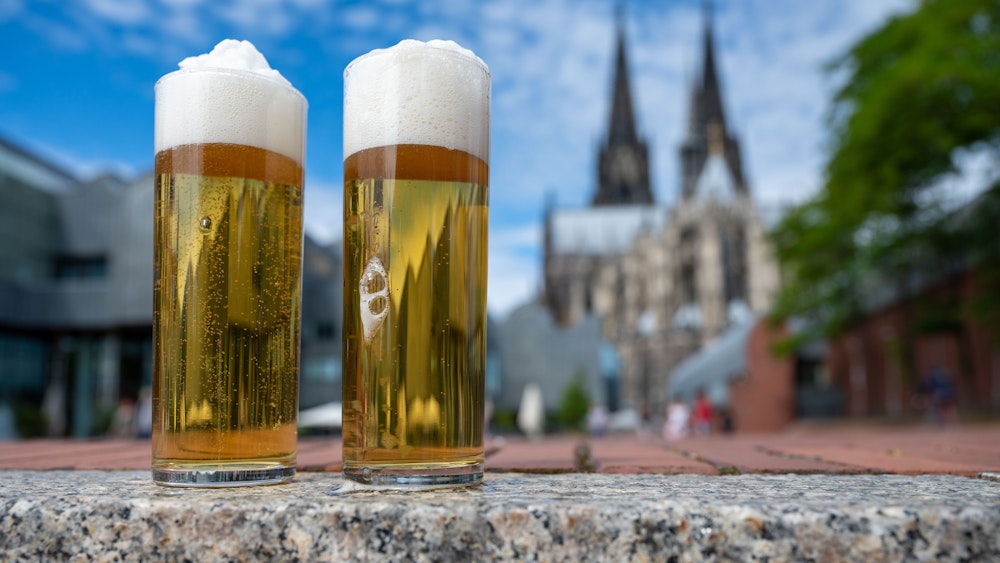 Kölsch im Glas, im Hintergrund ist der Kölner Dom zu sehen.