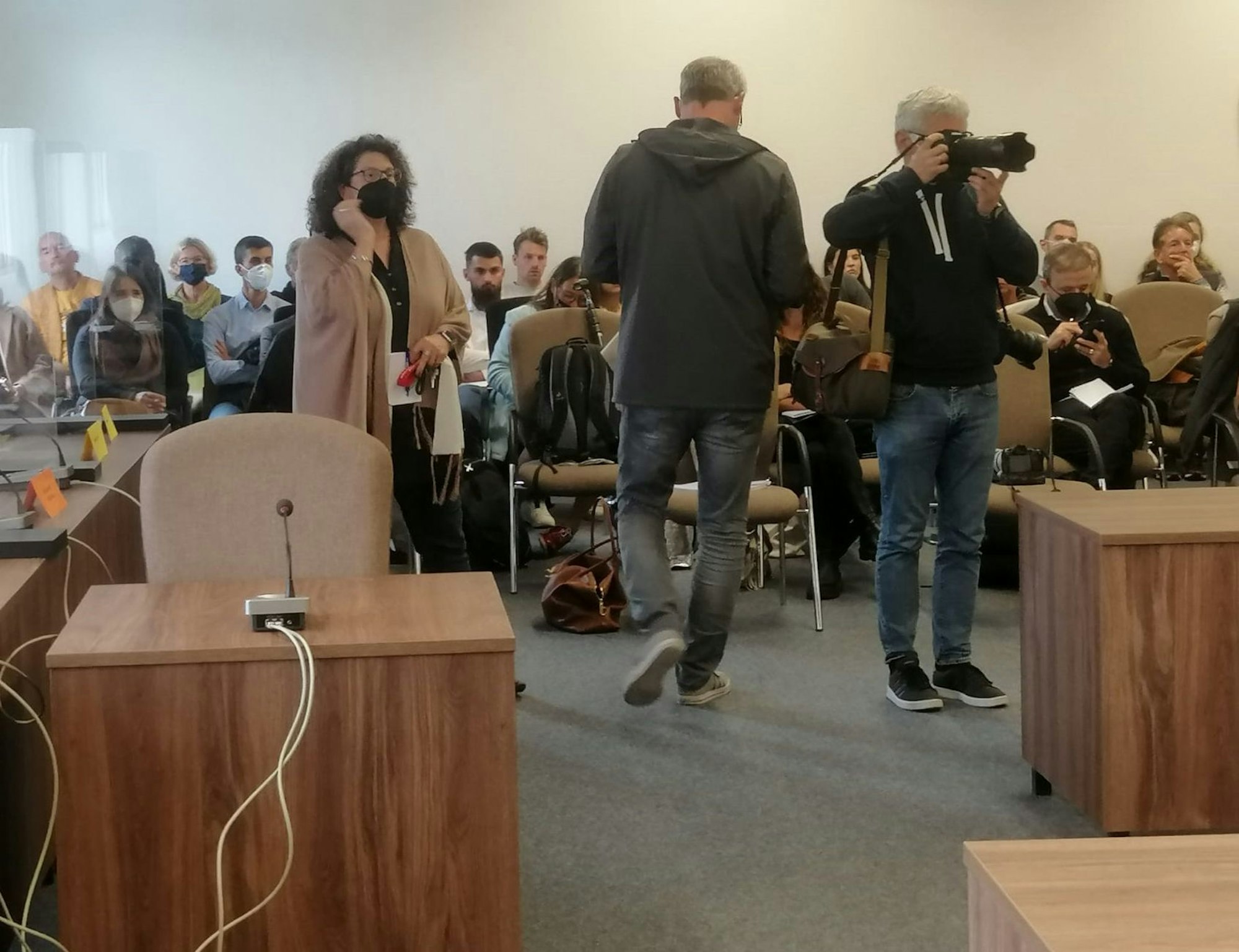 In dem Gerichtssaal sitzen viele Pressevertreter und Zuschauer.
