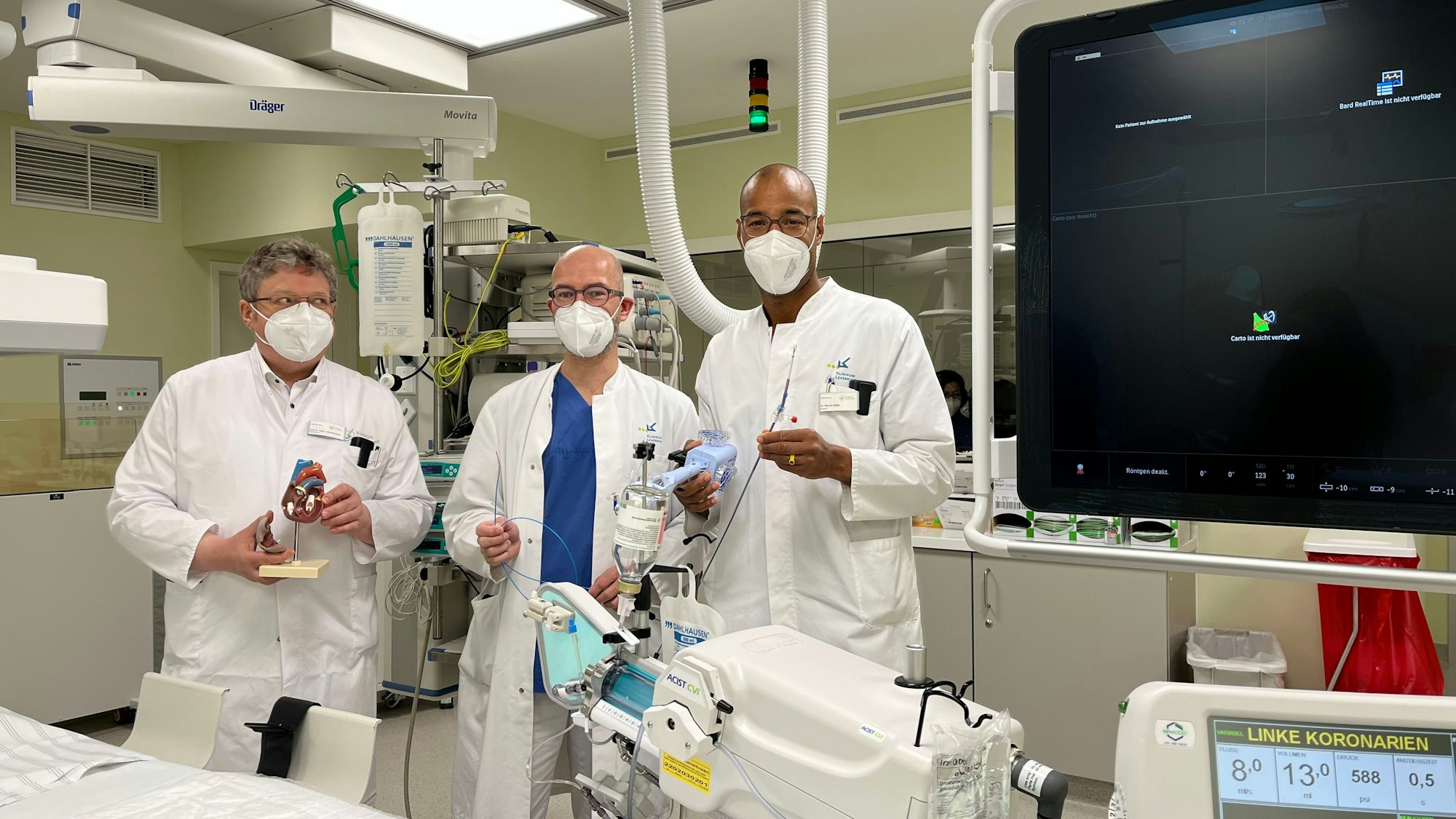 Drei Ärzte in weißen Kitteln stehen mit medizinischen Instrumenten in einem Herzkatheter-Labor.