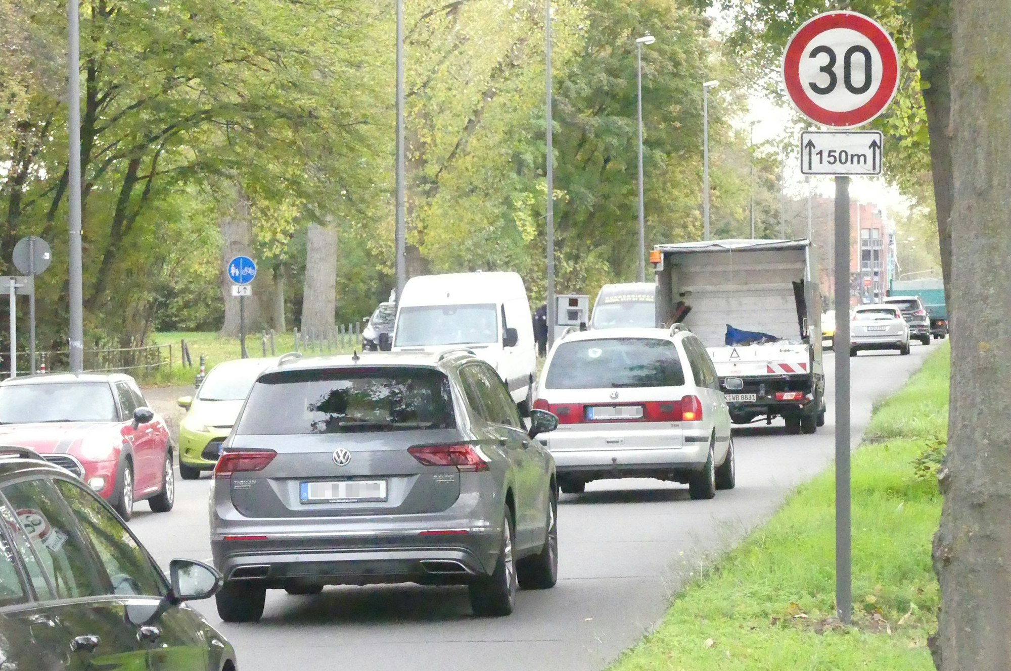 Autos fahren auf der Äußeren Kanalstraße, ein Tempo-30-Schild und ein mobiles Blitzgerät stehen am Fahrbahnrand.