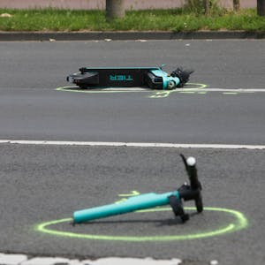 Auf der Straße liegen Wrackteile eines E-Scooters auf dem Asphalt