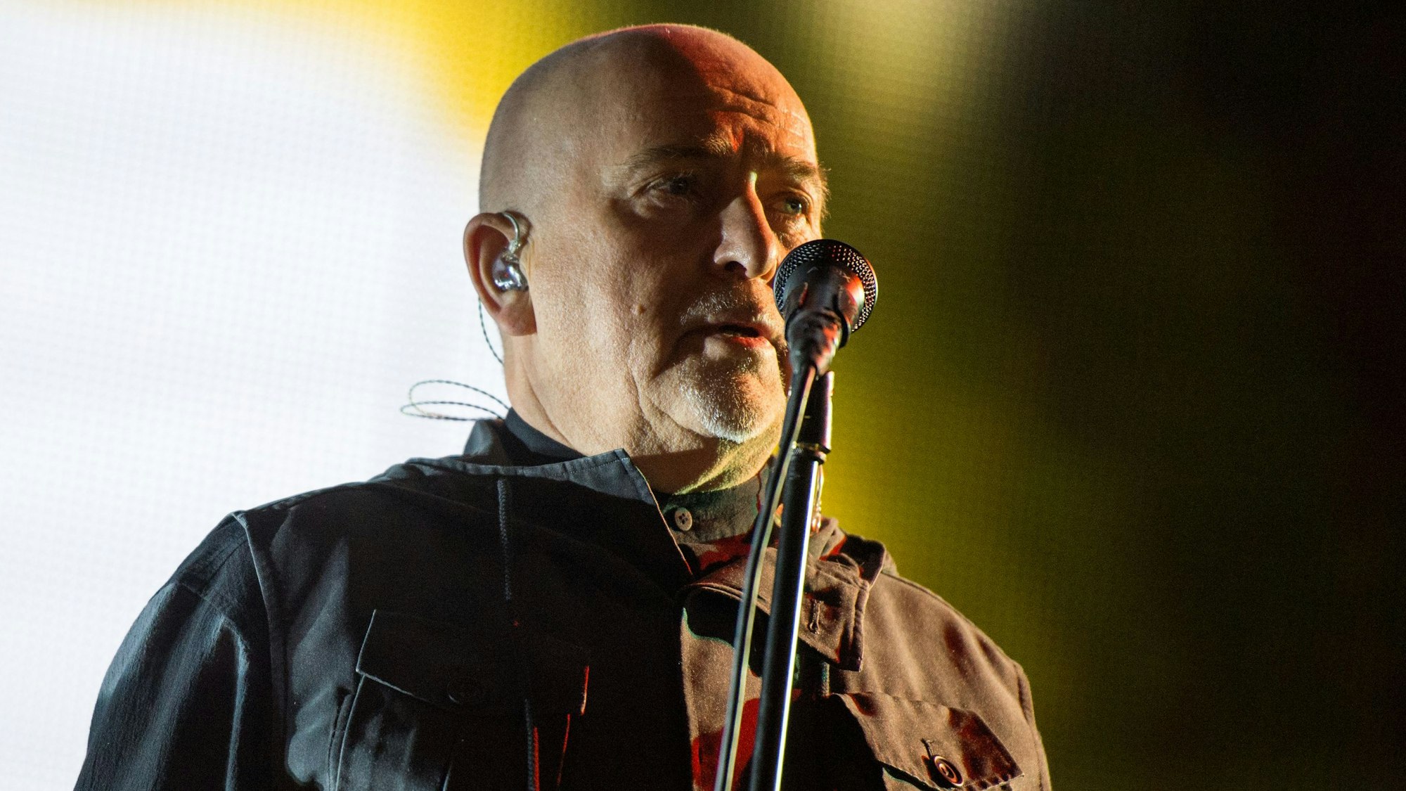 Peter Gabriel steht auf der Bühne und singt ins Mikrofon