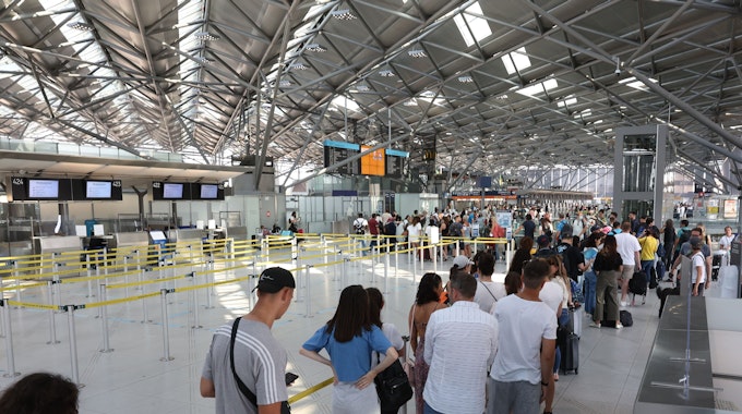 Lange Schlange am Flughafen Köln/Bonn. Reisende kommen mit Verspätung in den Urlaub.