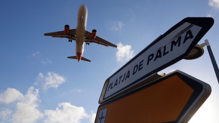 Ein Flugzeug überfliegt bei der Landung auf Mallorca ein Schild, das die Richtung nach Playa de Palma anzeigt.