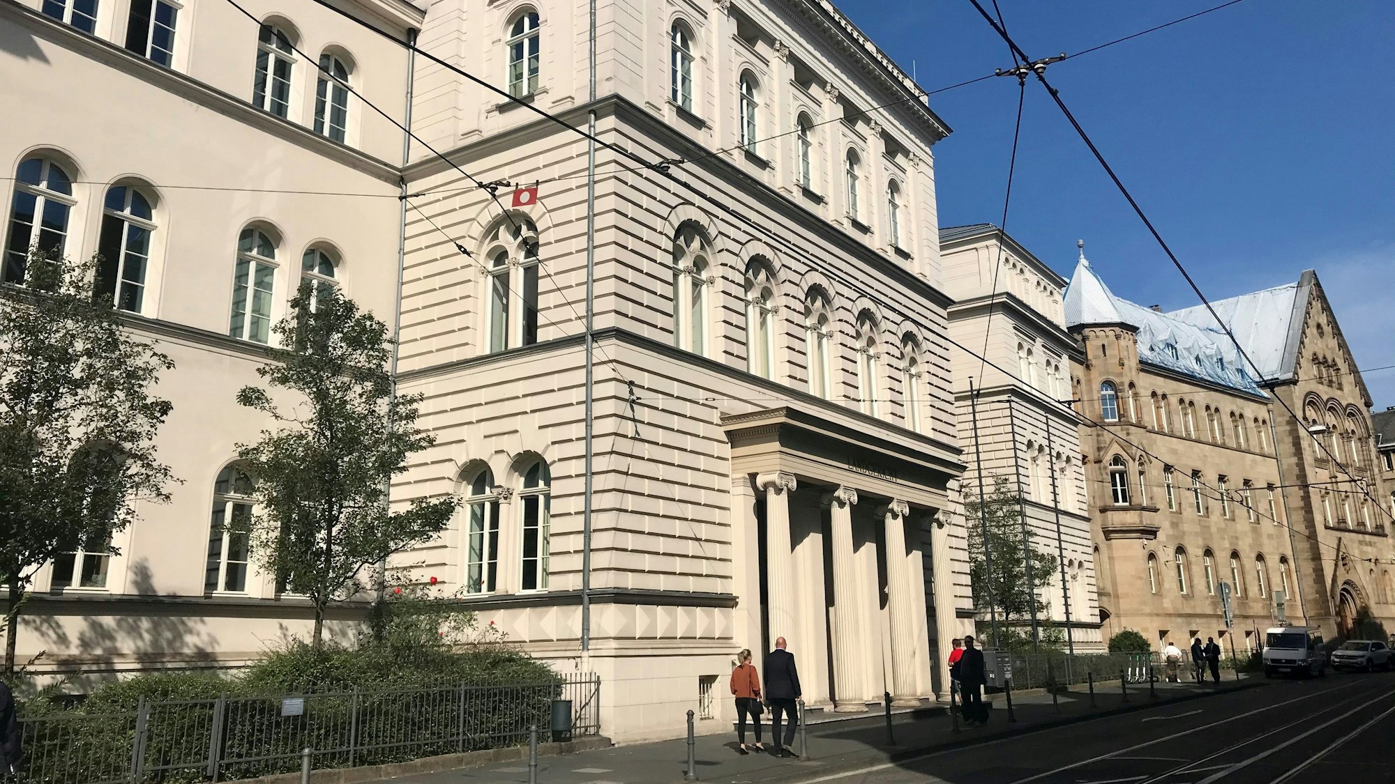 Das Gebäude des Landgerichts Bonn, Menschen gehen auf dem Bürgersteig davor.
