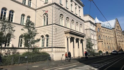 Das Gebäude des Landgerichts Bonn, Menschen gehen auf dem Bürgersteig davor.