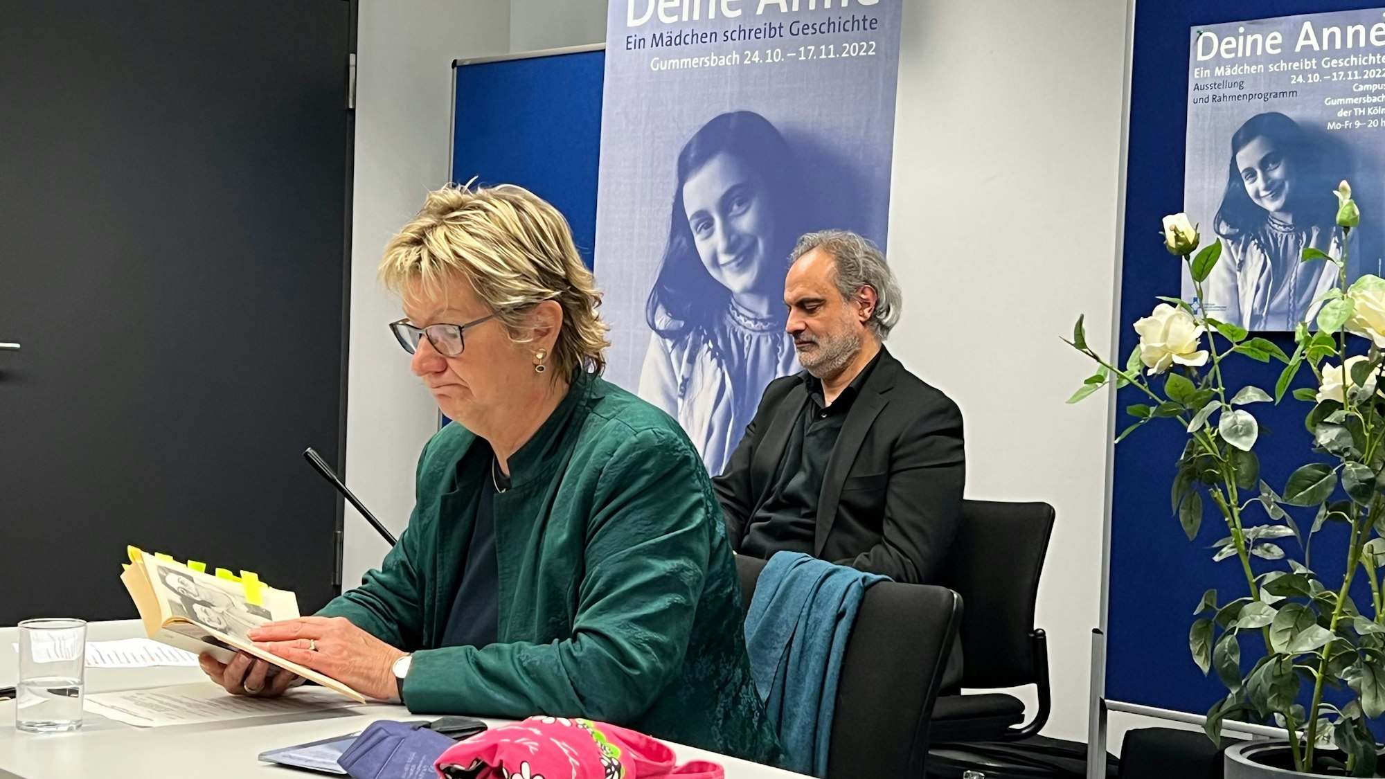 Die ehemalige stellvertretende NRW-Ministerpräsidentin Sylvia Löhrmann sitzt an einem Tisch und hat das Tagebuch der Anne Frank in der Hand.