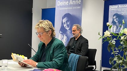 Die ehemalige stellvertretende NRW-Ministerpräsidentin Sylvia Löhrmann sitzt an einem Tisch und hat das Tagebuch der Anne Frank in der Hand.&nbsp;
