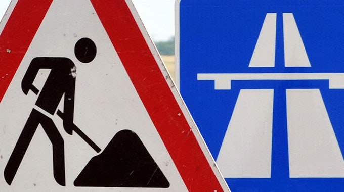 Ein Baustellenschild ist vor einem Autobahnschild platziert.