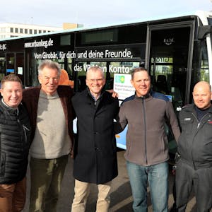 Fünf beteiligte Männer der Städtepartnerschaft Bergisch Gladbach-Butscha stehen Arm in Arm vor einem Bus.