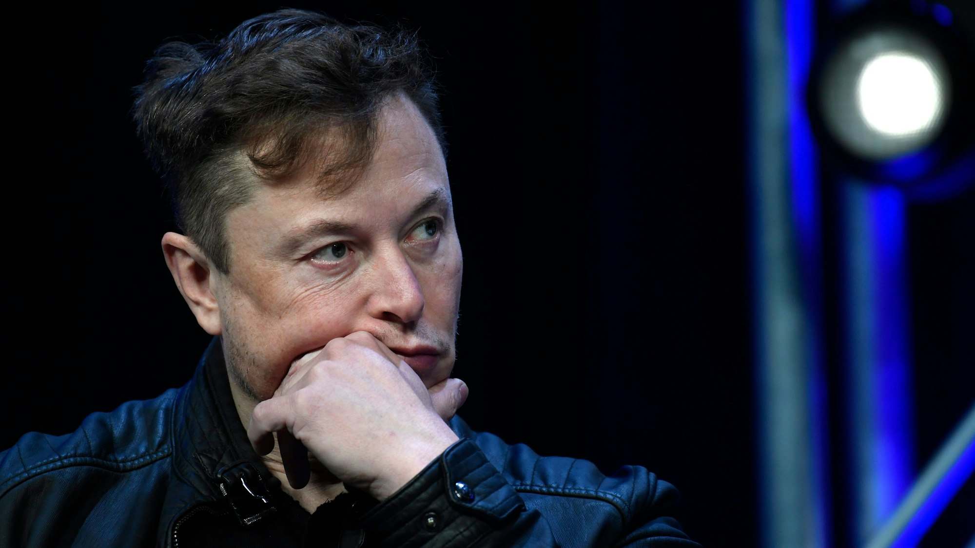 Elon Musk sitzt auf einer Bühne und wird in der Nahaufnahme gezeigt.