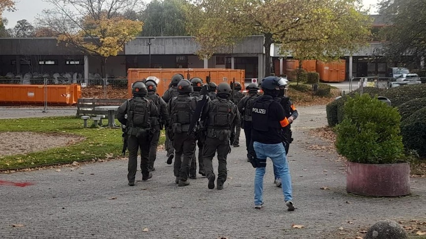Einsatzkräfte mit schusssicheren Westen und Helmen betreten das Gelände der Schule an der Zeithstraße.