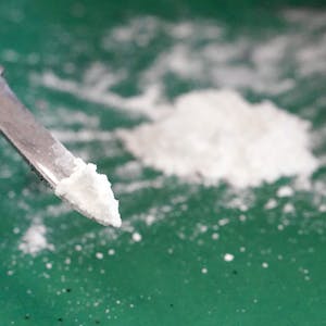 Kokain, ein weißes Pulver, liegt auf einer grünen Folie und auf der Spitze eines Taschenmessers.