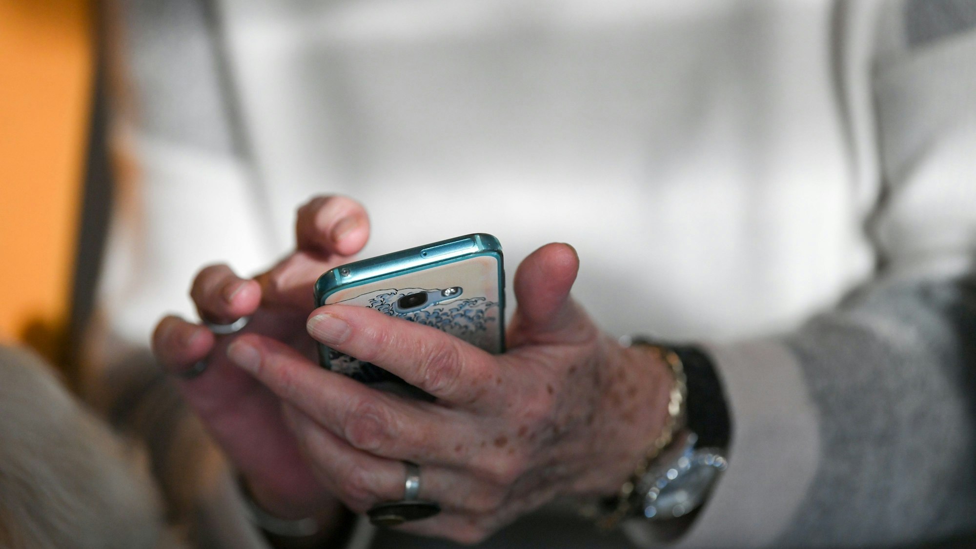 Eine Seniorin hält ihr Smartphone in den Händen.