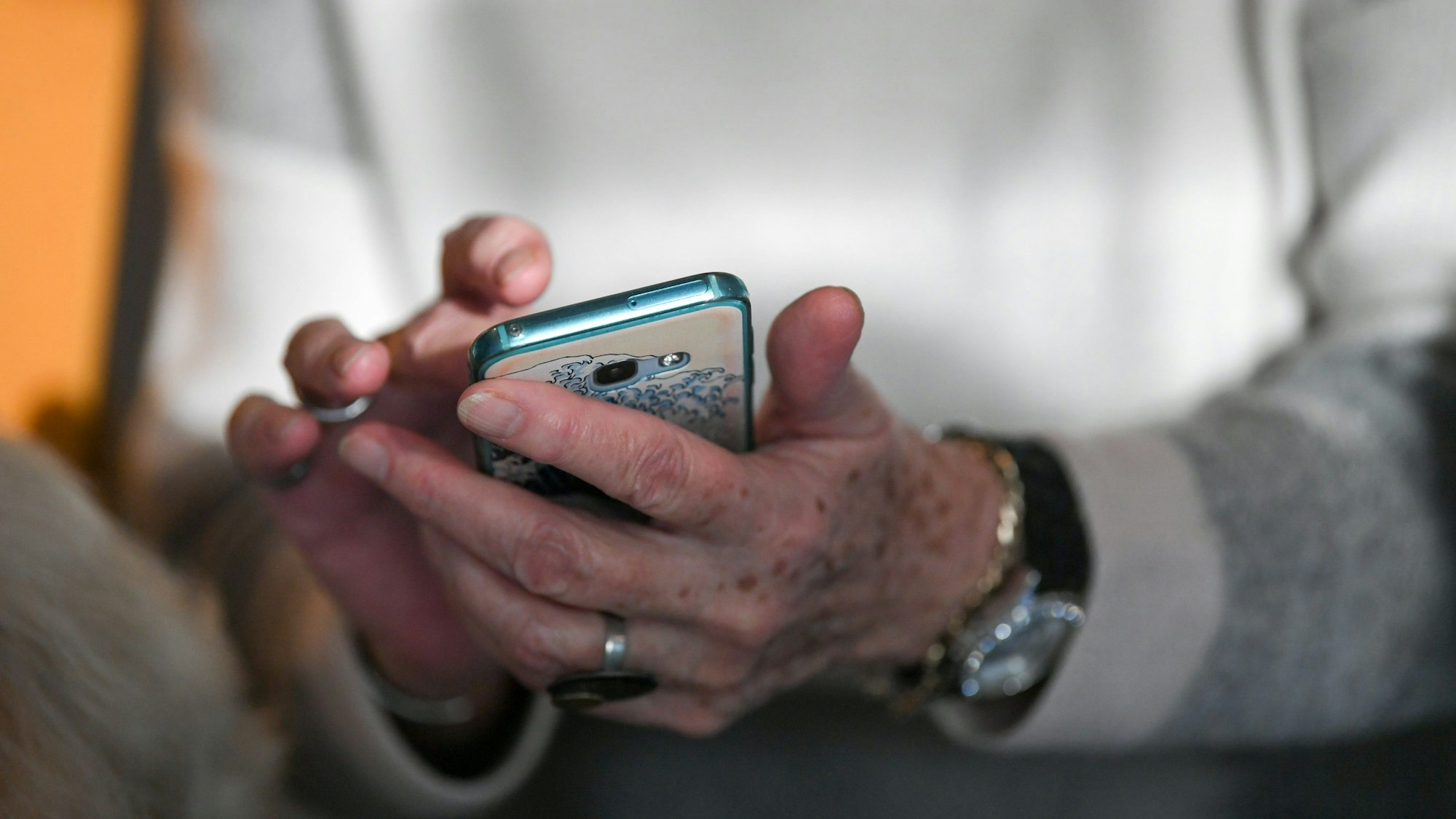 Eine Seniorin hält ein Smartphone in der Hand und tippt auf dem Bildschirm.